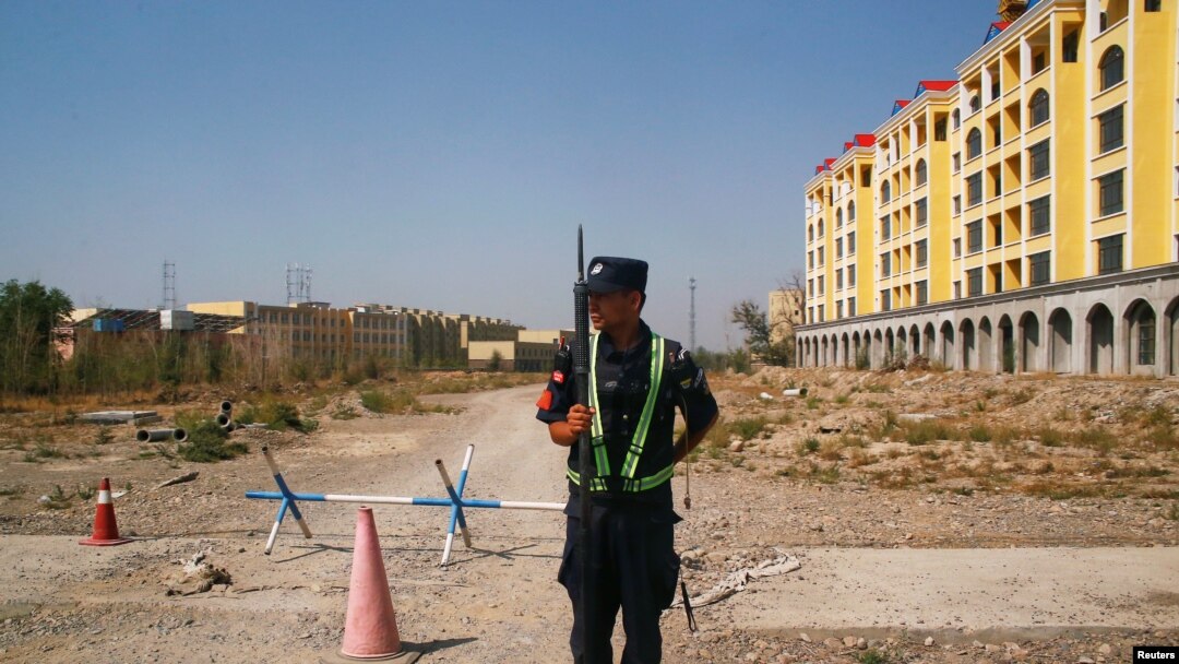 FILE - A Chinese police officer takes his position by the road near what is officially called a vocational education center in Yining in Xinjiang Uighur Autonomous Region, China, Sept. 4, 2018. 