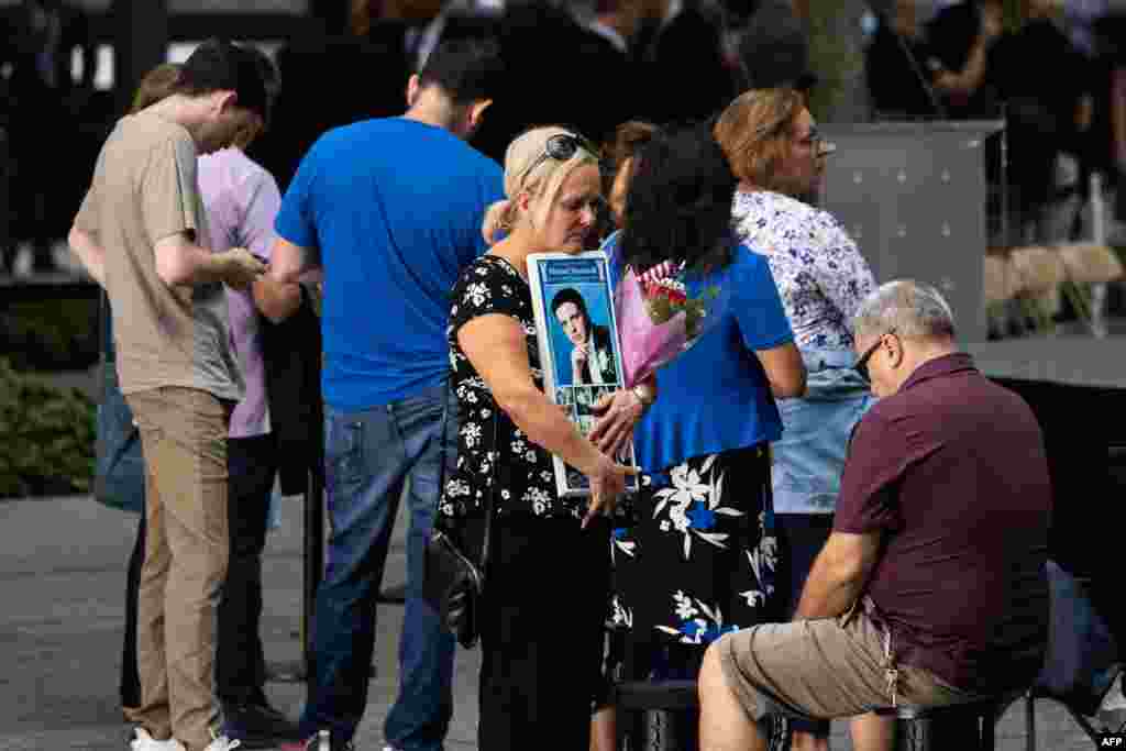 A relative of a victim holds an image and flowers at the 9/11 Memorial in New York City, Sept. 11, 2022.