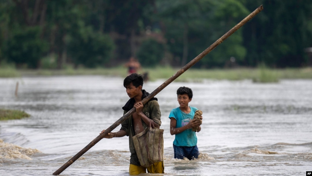 Boys wade through floodwaters in Bali village, west of Guwahati, India, June 23, 2023. Tens of thousands of people have moved to relief camps with one person swept to death by flood waters caused by monsoon rains battering villages in India’s northeast.
