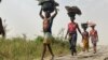 FILE - Women and children return from their farmlands after the day's work in Agatu village in Nigeria, Jan 5, 2022. The U.N. warns that the lean season in the country will heighten food security and nutrition crises there.