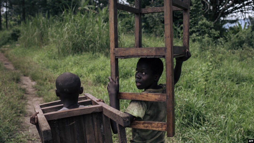 Watoto wawili wa kiume wakihamisha samani kutoka shule iliyokuwa ikitumiwa na kundi la waasi la M23 kama kituo cha kijeshi huko Kishishe DRC, tarehe 5 Aprili. Picha na ALEXIS HUGUET / AFP. 