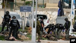A polícia israelita ao lado dos corpos de militantes fora da esquadra de polícia que foi invadida por homens armados do Hamas no sábado, em Sderot, Israel, domingo, 8 de outubro de 2023.