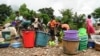 Women and children wash plastic kitchen utensils in a stream in Phalombe, southern Malawi, March 17, 2023. The area was hard hit by Cyclone Freddy. 