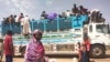 FILE - People board a truck as they leave Khartoum, Sudan, June 19, 2023.