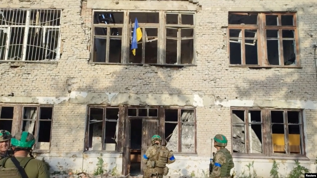 Ukrainian soldiers stand under a Ukrainian flag during an operation that claims to liberate a village named as Blahodatne, Donetsk Region, Ukraine, in this screengrab from a handout video released June 11, 2023. (68th Separate Hunting Brigade 'Oleksy Dovbusha'/via Reuters)