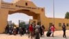 Evacuees carry their luggage as they cross into Egypt through the Argeen land port after being evacuated from Sudan to escape the conflict, on the international border lines between Egypt and Sudan, April 27, 2023.