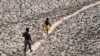FILE - A man and a boy walk across the dried bed of the Yamuna River in New Delhi, India, May 2, 2022. In an annual climate report, the World Meteorological Organization said Nov. 2, 2023, that the climate crisis was generating a global health crisis.