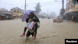 Um homem atravessa as águas das cheias ao longo de uma rua na sequência de fortes chuvas no distrito de Kisauni, em Mombaça, no Quénia.