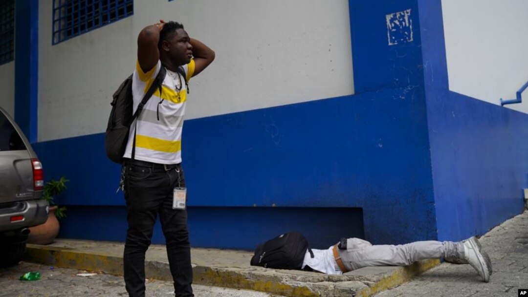 El periodista haitiano Romelo Vilsaint, quien falleció tras ser baleado, yace boca abajo en el estacionamiento de un departamento policial de Puerto Príncipe, Haití, el domingo 30 de octubre de 2022. (AP Foto)