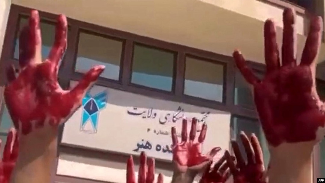 This image grab from a UGC video made available on Twitter Oct. 9, 2022, shows Iranian students from the Faculty of Arts at Tehran's Azad University participating in a protest with their palms covered in red paint to symbolize blood.