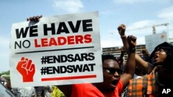 FILE - People hold banners as they protest against police brutality at Lekki toll gate in Lagos, Nigeria, Oct. 15, 2020. Protests started in Lagos against a police unit known as the Special Anti-Robbery Squad, or SARS, which faced widespread accusations of brutality.