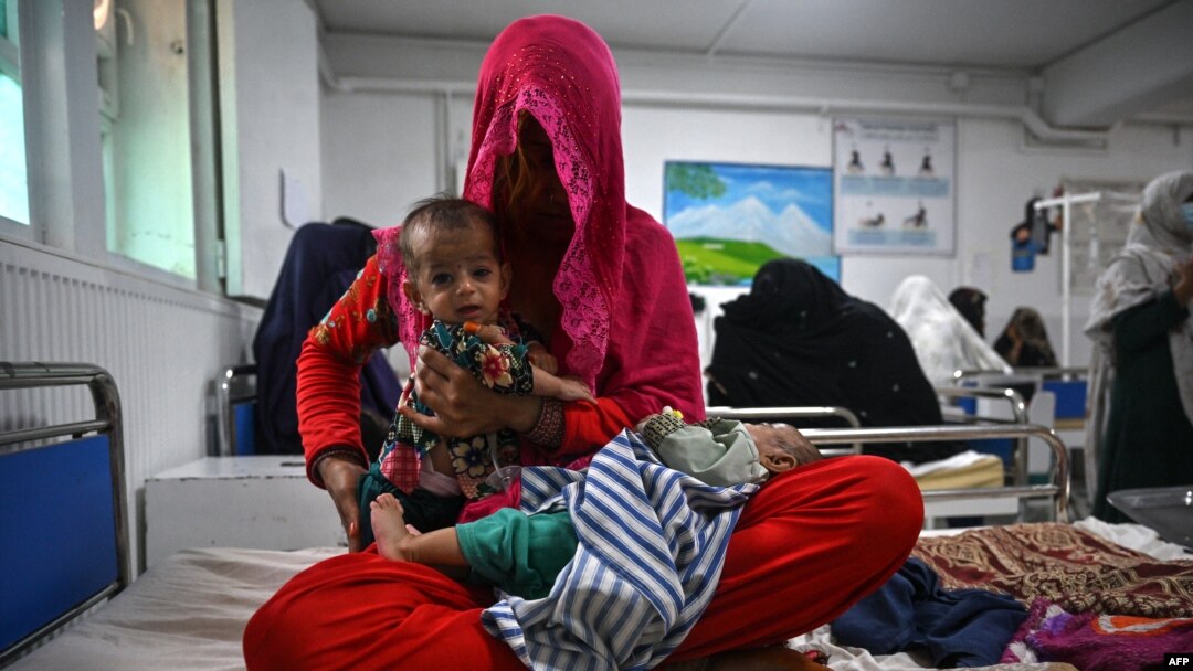 FILE - A woman sits on a hospital bed with her four-month-old twins in the malnutrition ward at the Boost Hospital, run by Medicines Sans Frontiers (MSF), in Lashkar Gah, Helmand, Afghanistan, July 21, 2022.