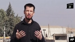 FILE - In this still image taken from an undated video published on the Internet by the Islamic State group militants, captive British journalist John Cantlie speaks into a camera in what he identifies as the embattled Syrian town of Kobani. 