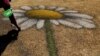 A person touches a land art created by French-Swiss land artist Guillaume Legros (Saype), invented from an eco-responsible paint composed mainly of chalk and charcoal, on the lawns of the UNEP in Gigiri, Nairobi, March 3, 2022. 