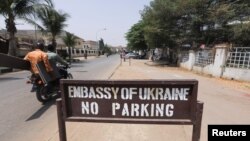 FILE - Men on a motorbike ride past a sign for the Ukrainian embassy in Abuja, Nigeria, Feb. 25, 2022.
