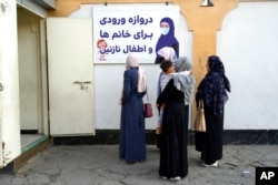 Afghan women stand outside an amusement park, in Kabul, Nov. 10, 2022. The Taliban have banned women from using gyms and parks in Afghanistan, part of their crackdown on women's rights and freedoms.