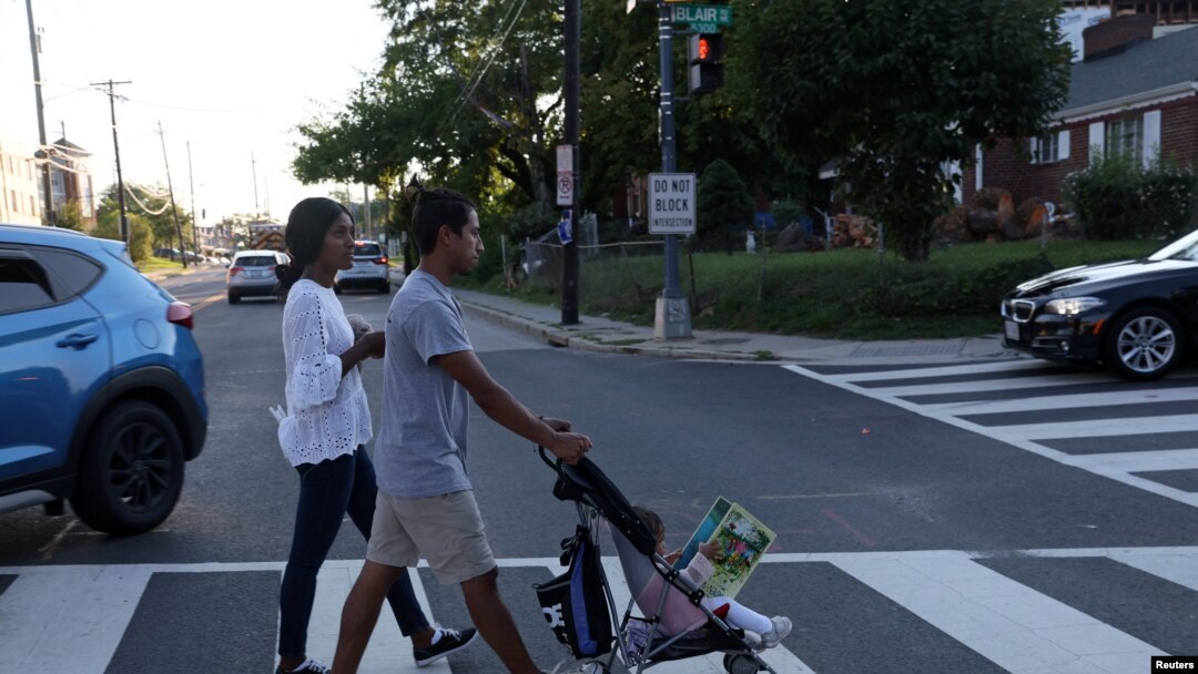 Una pareja colombiana se dirige a una parada de autobús para llevarlos de regreso al hotel en el que se hospedan con su hija Evangeline, de 1 año, luego de visitar el Mary's Center en Washington, EEUU, el 23 de agosto de 2022.