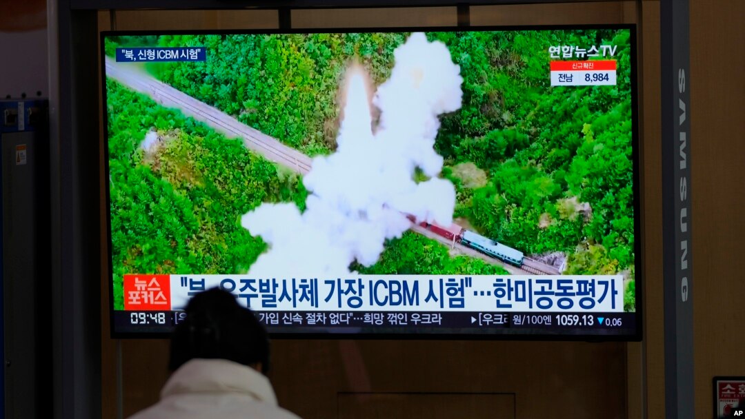 A visitor watches a TV screen showing a news program reporting about North Korea's missile with file footage at a train station in Seoul, South Korea, March 11, 2022
