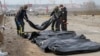 FILE - Ukrainian soldiers collect bodies of civilians killed by the Russian forces at the destroyed bridge in Irpin close to Kyiv, Ukraine, March 31, 2022.
