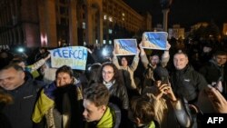 People hold a slogan which reads "11/11/2022 - Kherson - Ukraine" as they gather in Maidan square to celebrate the liberation of Kherson, in Kyiv on November 11, 2022, amid the Russian invasion of Ukraine. - Ukraine's President Volodymyr Zelensky said on 