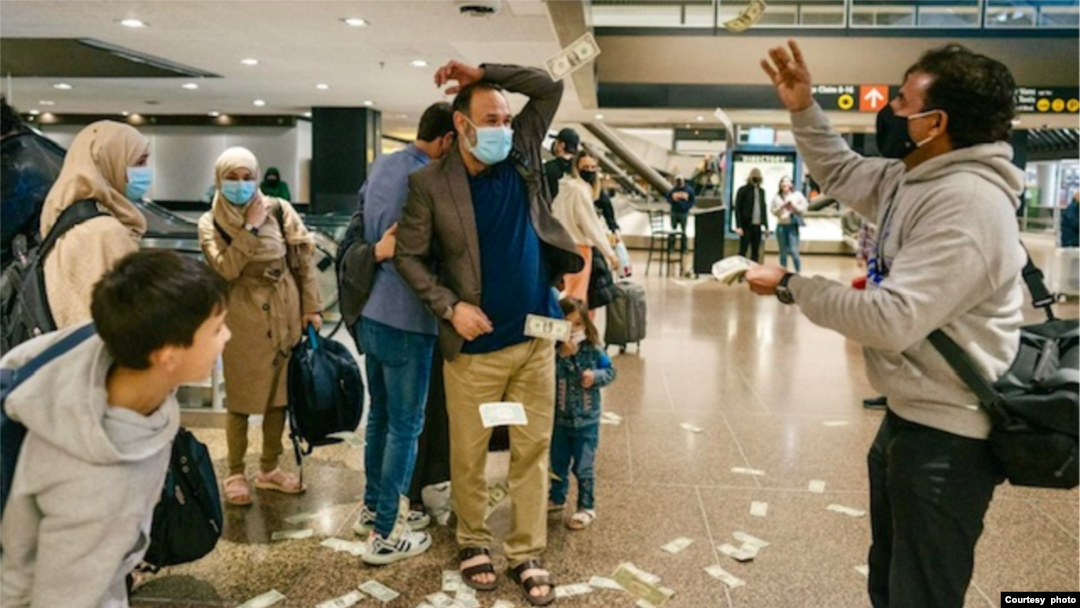 US dollar bills shower Afghan refugee Najeebullah and his family as they arrive at the Seattle International Airport. (Photo by Joshua Trujillo)