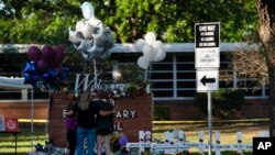 A family pays their respects next to crosses bearing the names of Tuesday's shooting victims at Robb Elementary School in Uvalde, Texas, May 26, 2022. 