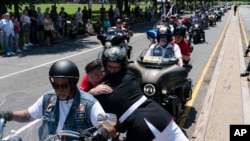 U.S. Marine Corps Staff Sgt. Tim Chambers hugs a participant in the "Rolling to Remember" motorcycle rally on May 29, 2022. Organizers staged the Washington-area ride to spotlight issues facing veterans, demand action for those missing, and raise awareness of the prevalence of suicide among veterans.
