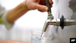An official at the Carlsbad Desalination plant fills a cup with filtered water made from ocean water, May 26, 2022, in Carlsbad, Calif.