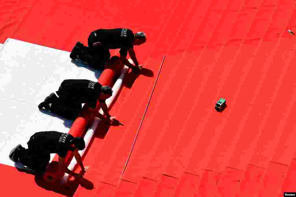 Workers install the red carpet in front of the main entrance of the Festival Palace on the day of the opening ceremony of the 75th Cannes Film Festival in Cannes, France.