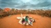 FILE - A Somali woman and child wait to be given a spot to settle at a camp for displaced people amid a drought on the outskirts of Dollow, Somalia on Sept. 20, 2022. 