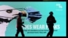 FILE - Essential workers walk past a "Heroes Wear Masks" sign during a seven-day lockdown as the state of Victoria looks to curb the spread of COVID-19 in Melbourne, Australia, May 28, 2021. 