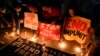 FILE - Activists light candle beside slogans as they condemn the killing of Filipino journalist Percival Mabasa during a rally in Quezon city, Oct. 4, 2022. Authorities filed murder complaints against a top prison official and an aide who they accused of 