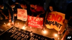 FILE - Activists light candle beside slogans as they condemn the killing of Filipino journalist Percival Mabasa during a rally in Quezon city, Oct. 4, 2022. Authorities filed murder complaints against a top prison official and an aide who they accused of 
