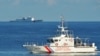 This file photo taken on May 14, 2019 shows a Philippines' coast guard ship (R) sailing past a Chinese coast guard ship during a joint search and rescue exercise between the Philippines and US coast guards near Scarborough Shoal in the South China Sea.