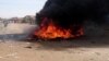 FILE - A bonfire is lit along a street during protests against price increases in Atbara, Nile River state, Sudan, Dec. 20, 2018.