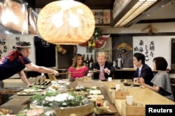U.S. President Donald Trump, with first lady Melania Trump, receives a plate of food from a chef as they and Japanese Prime Minister Shinzo Abe and his wife Akie Abe have dinner in Tokyo, May 26, 2019.
