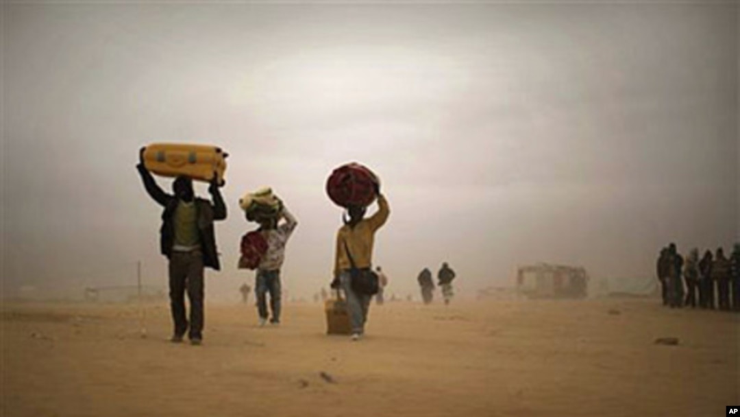 Men who used to work in Libya and fled the unrest in the country, carry their belongings as they walk during a sand storm in a refugee camp in Ras Ajdir, Tunisia (File Photo)