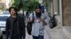 FILE - A man uses his cellphone while walking on a sidewalk in downtown Tehran, Iran, April 18, 2018.