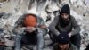 People react as they sit on the wreckage of collapsed buildings, in Aleppo, Syria, Tuesday, Feb. 7, 2023. (AP Photo/Omar Sanadiki)