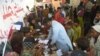 FILE - Families displaced by floods gather around a paramedic at a makeshift medical camp set in Dadu district, Sindh province in Pakistan on Sept. 27, 2022.
