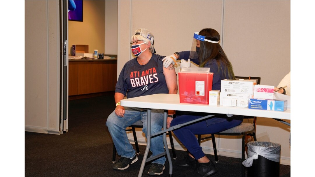 Lucinda Shelton of Acworth, Georgia, receives her covid vaccination administered by a worker from Emory Healthcare at the ball park prior to the game between the Atlanta Braves and the Philadelphia Phillies at Truist Park.