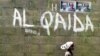 A girl walks past a wall with graffiti about the al-Qaida network in a Muslim area of the northern city of Kano, Nigeria, (File photo).