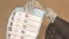 A Togolese electoral holds up a ballot papers in a polling station in Lome, 04 Mar 2010