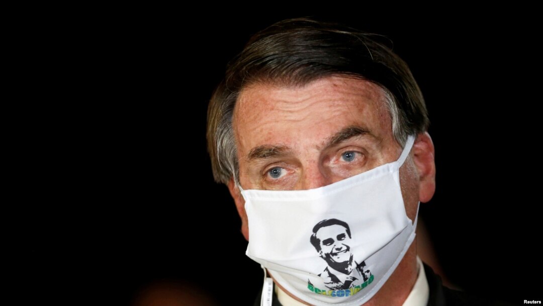 FILE - Brazil's President Jair Bolsonaro speaks with journalists while wearing a protective face mask as he arrives at Alvorada Palace, amid the coronavirus disease (COVID-19) outbreak, in Brasilia, Brazil.