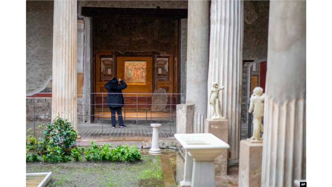 A woman takes pictures of the "triclinium", or dining room, called Hall of Pentheus, part of the Ancient Roman Domus Vettiorum, House of Vettii (AP Photo/Andrew Medichini)