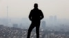 FILE - A man stands in front of a general view of Tehran city following the increase in air pollution in Tehran, Iran, Nov. 24, 2021. 