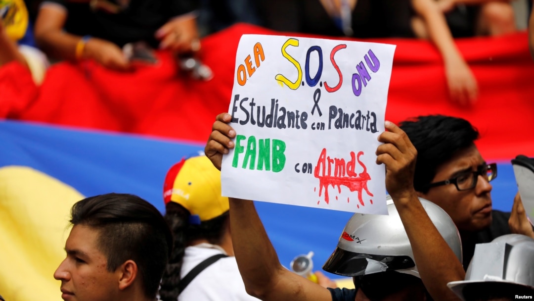 ARCHIVO - Un manifestante reclama con un cartel ayuda a la OEA y a la ONU para hacer frente a la crisis que atraviesa el país en junio de 2017.