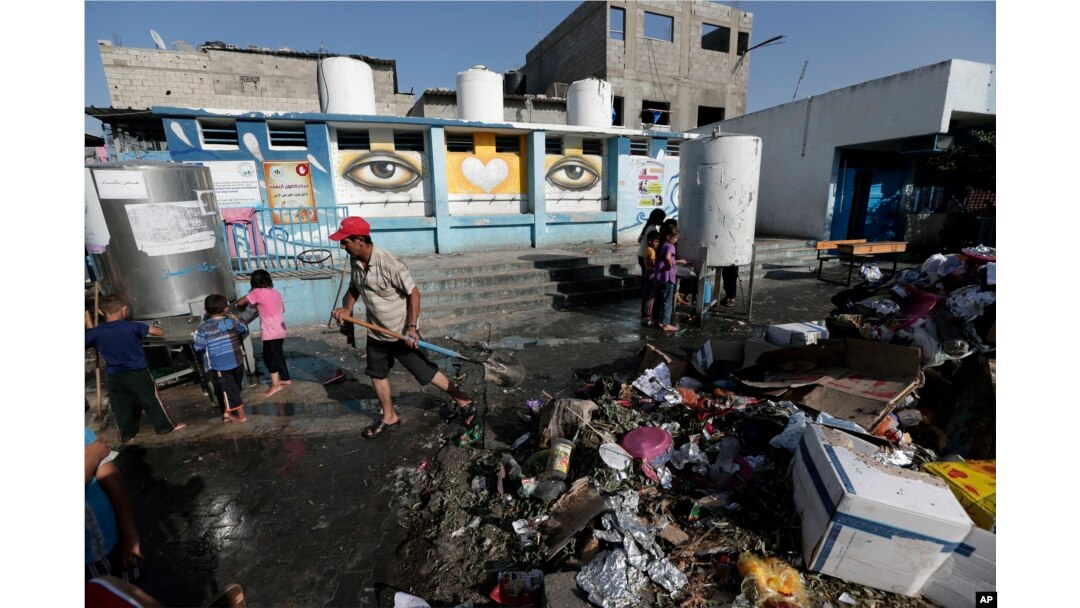 A U.N. worker cleans the garbage at the courtyard of the Abu Hussein U.N. school at Jebaliya refugee camp, northern Gaza Strip, July 30, 2014.