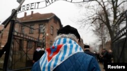 Preživeli i gosti prolaze pored natpisa "Rad oslobađa" na kapiji bivšeg nacističkog logora smrti Aušvic, tokom ceremonije povodom 73. godišnjice oslobođenja logora i Međunarodnog dana sećanja na žrtve holokausta, u Osvijenćimu, Poljska, 28. januara 2018.