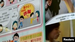 FILE - A person walks past an anti-scam poster in Taipei.
